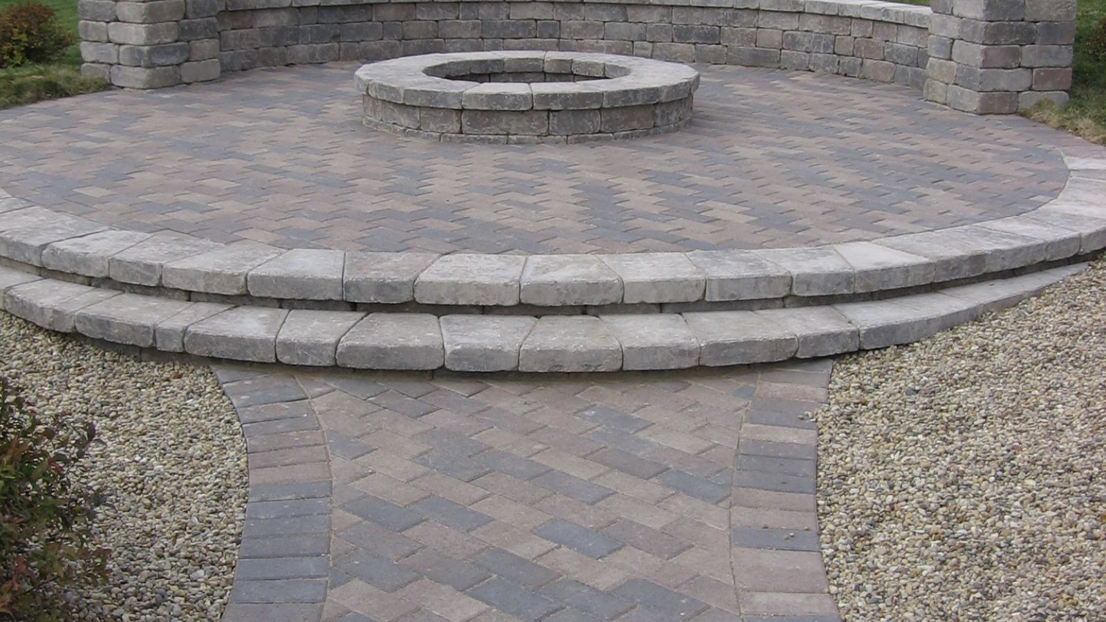 Finished brick walkway leading to a stone firepit 